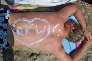 auf dem sonnengebräunten Rücken steht mit Sonnenmilch geschrieben: RKW und ein Smily