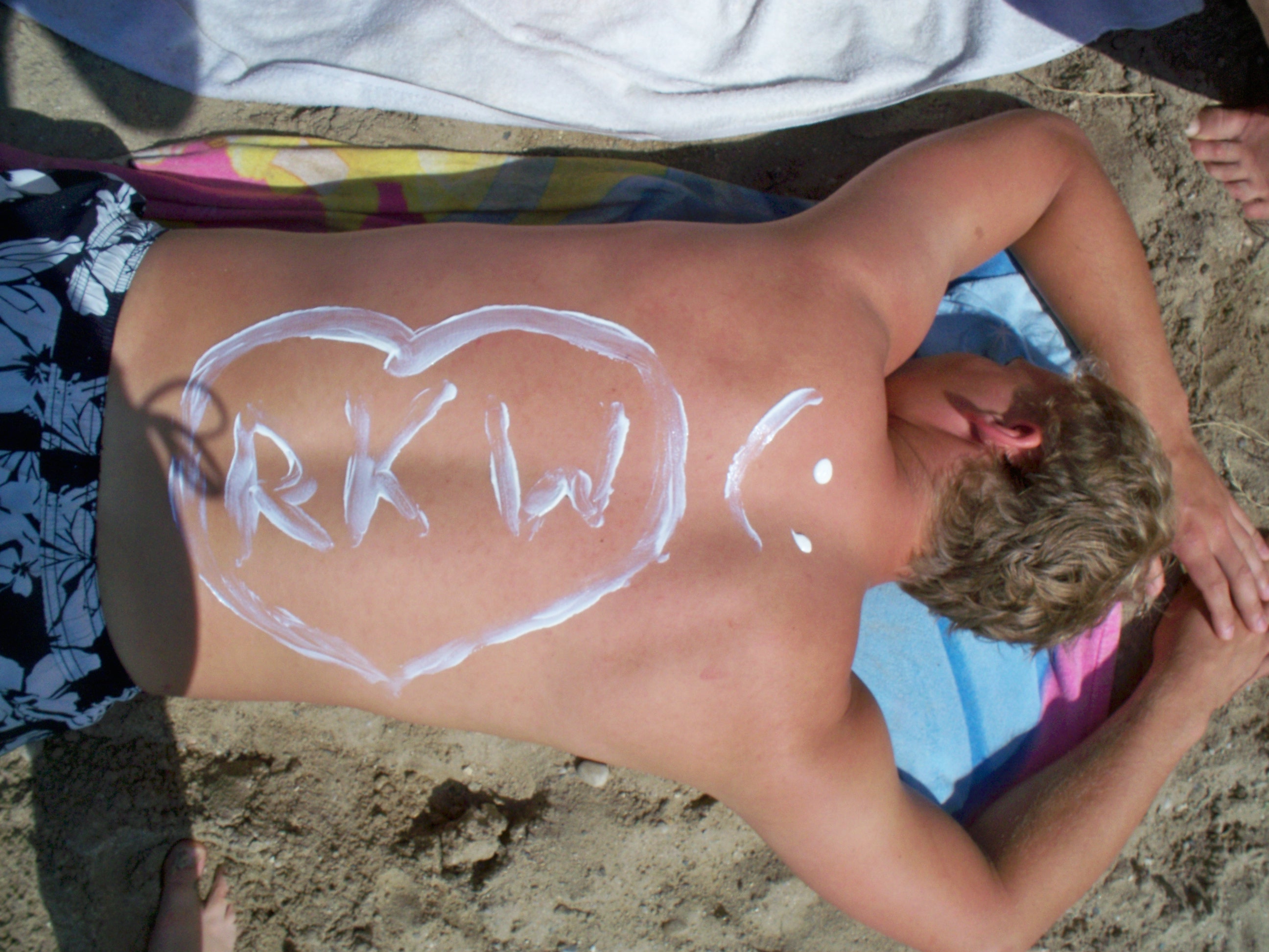 auf dem sonnengebräunten Rücken steht mit Sonnenmilch geschrieben: RKW und ein Smily