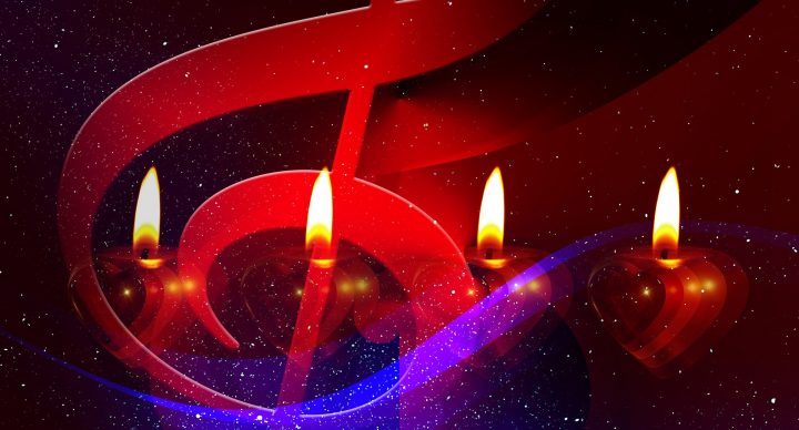 vier Kerzen schimmern hinter einem überdimensionalen Notenschlüssel