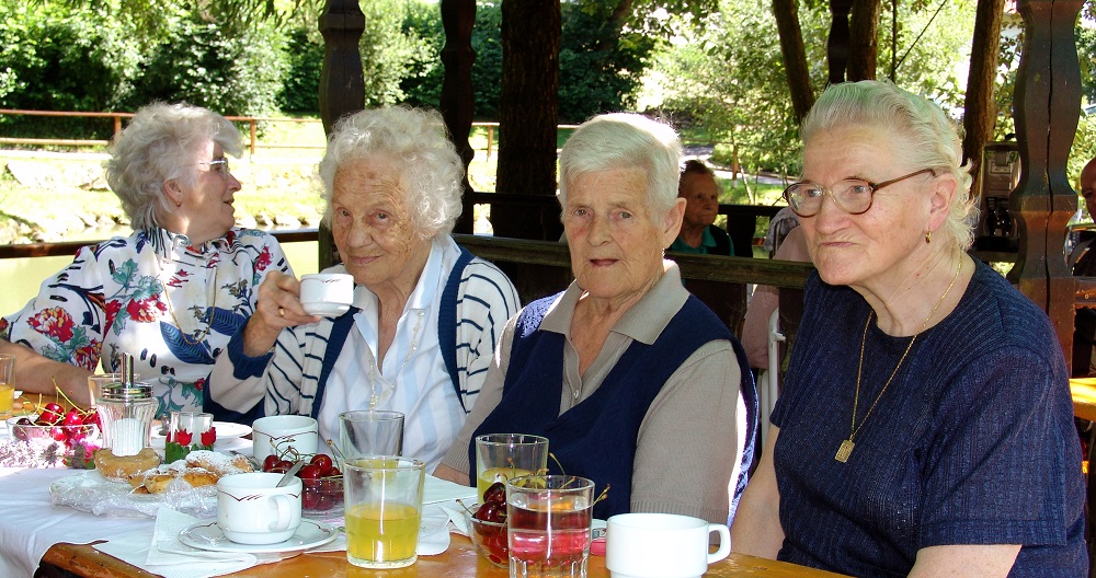 vier Seniorinnen beim Kaffeekränzchen im Freien